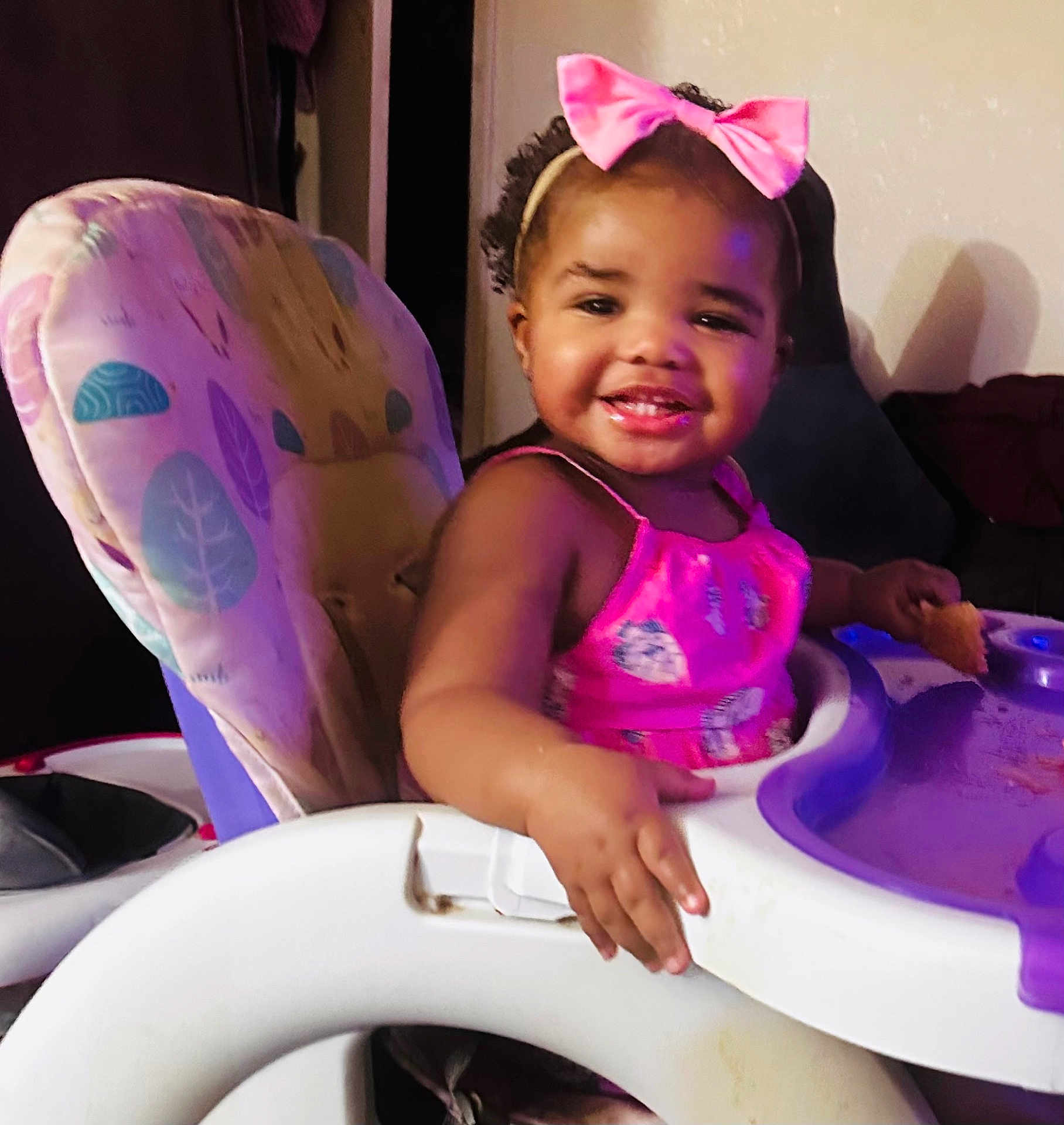 Jurnee joined the competition — help win amazing prizes! toddler, child, high_chair, pink_dress, bow, smiling, food, indoor, baby, seat, happy, person, curly_hair, playful, young_child, feeding, furniture, cute, portrait, home