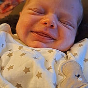 Yris a rejoint le concours — aidez-le/la à gagner de superbes lots ! baby, smiling, face, infant, onesie, clothing, star_pattern, sleeping, close_up, cute, child, newborn, happy, portrait, soft_light, indoor, cozy, young, peaceful, person