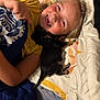 child, smiling, bed, blanket, puppy, dog, pet, lying_down, yellow_shirt, happy, indoor, cute, cozy, friendship, snuggling, sleeping, animal, person, face, hair