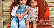 Hanish is registered to the contest to win money with this photo: barefoot, bench, boy, casual_clothing, children, curious, girl, holding_hands, long_hair, nature, outdoor, overalls, portrait, rustic, short_hair, siblings, smiling, sunlight, wooden_bench, wooden_wall