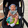 baby, stroller, headphones, bib, toy, smile, outdoor, sidewalk, clothing, infant, happy, seat, person, child, footwear, sock, black, colorful, play, accessory