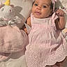 baby, infant, pink_dress, headband, plush_toy, unicorn, blanket, cute, smiling, lying_down, bunny_slippers, soft_texture, indoor, portrait, child, adorable, cozy, toddler, face, young_child