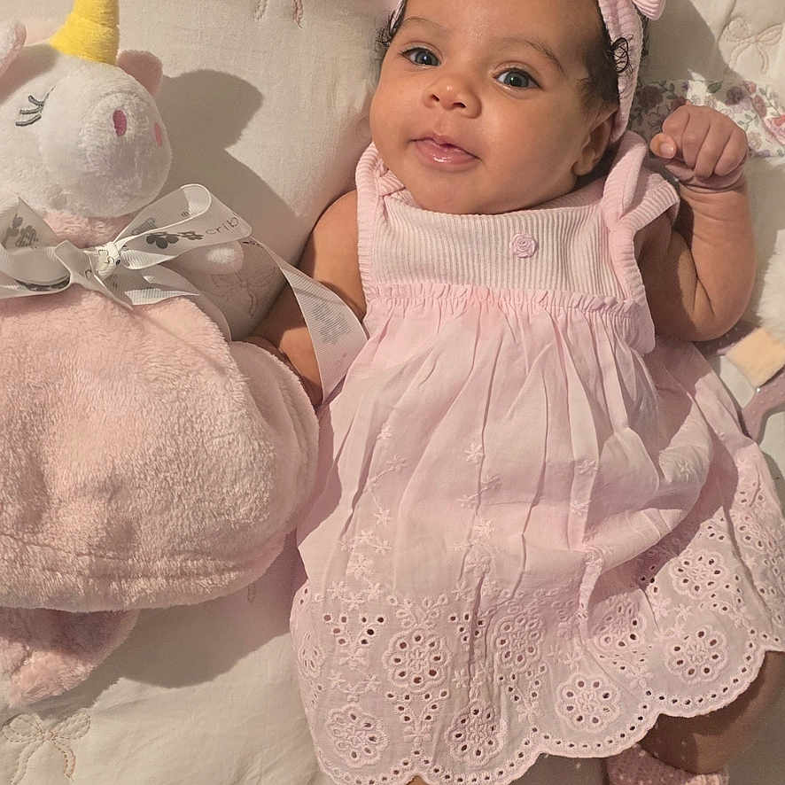Sky joined the competition — help win amazing prizes! baby, infant, pink_dress, headband, plush_toy, unicorn, blanket, cute, smiling, lying_down, bunny_slippers, soft_texture, indoor, portrait, child, adorable, cozy, toddler, face, young_child