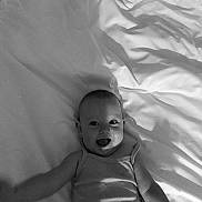 Adelina participe au concours pour gagner de l'argent avec cette photo : baby, smiling, bed, blanket, black_and_white, infant, happy, face, person, cute, child, sleepwear, portrait, young, indoors, soft, rest, lying_down, expression, skin