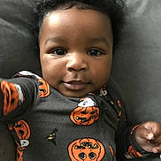 Richard joined the competition — help win amazing prizes! baby, black_hair, child, closeup, clothing, curly_hair, cute, face, ghost, halloween, hand, indoors, infant, lying_down, onesie, person, portrait, pumpkin, smiling, soft_surface