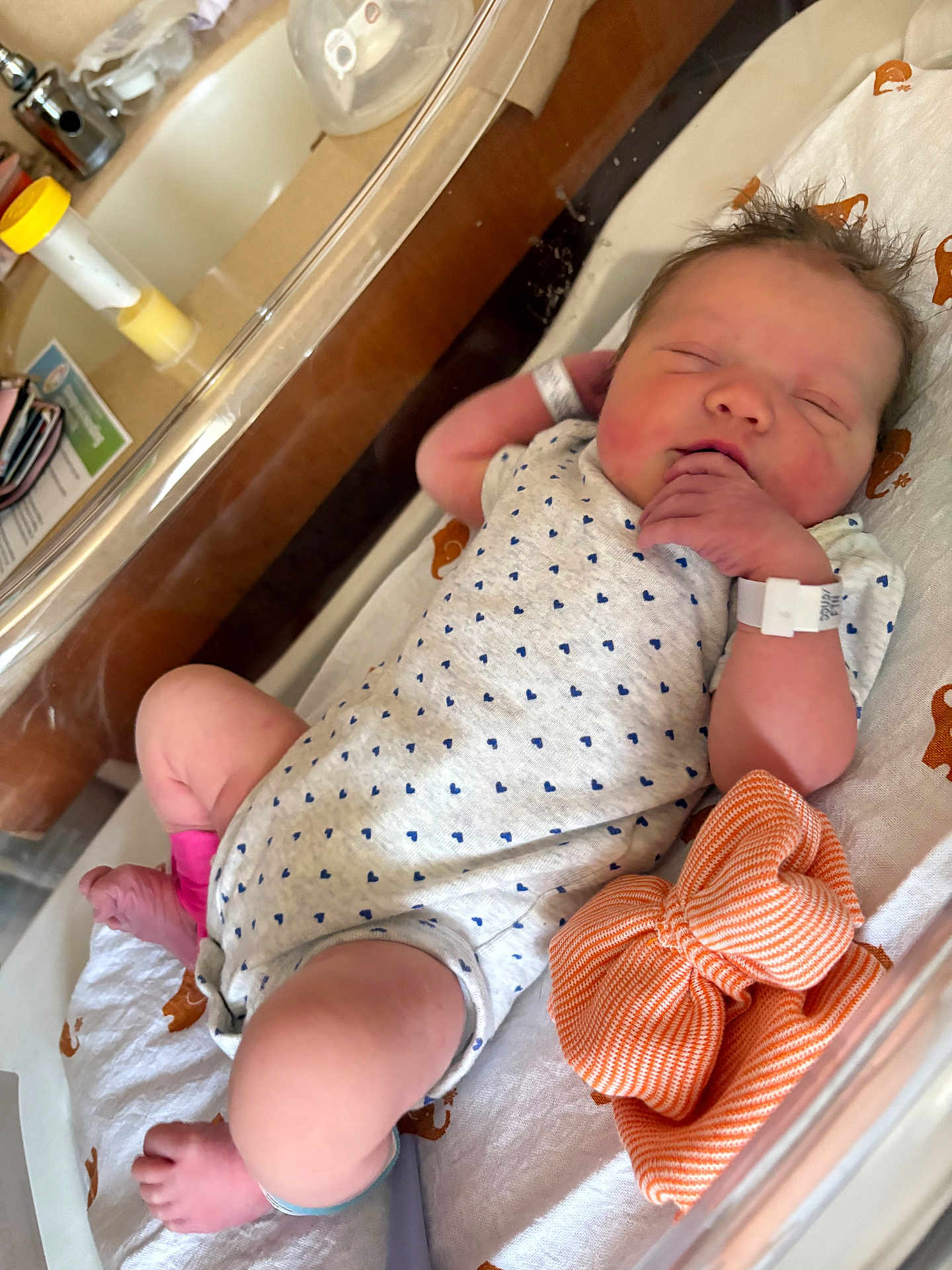 Ellie is registered to the contest to win money with this photo: newborn, baby, sleeping, hospital, bassinet, onesie, infant, person, clothing, wristband, ankleband, orange_cloth, cute, peaceful, skin, hand, foot, bed, blanket, indoor