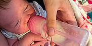 Ellie is registered to the contest to win money with this photo: baby, feeding, bottle, hand, foot, infant, newborn, person, blanket, clothing, skin, nourishment, care, closeup, indoors, soft_lighting, human, parent, rest, comfort