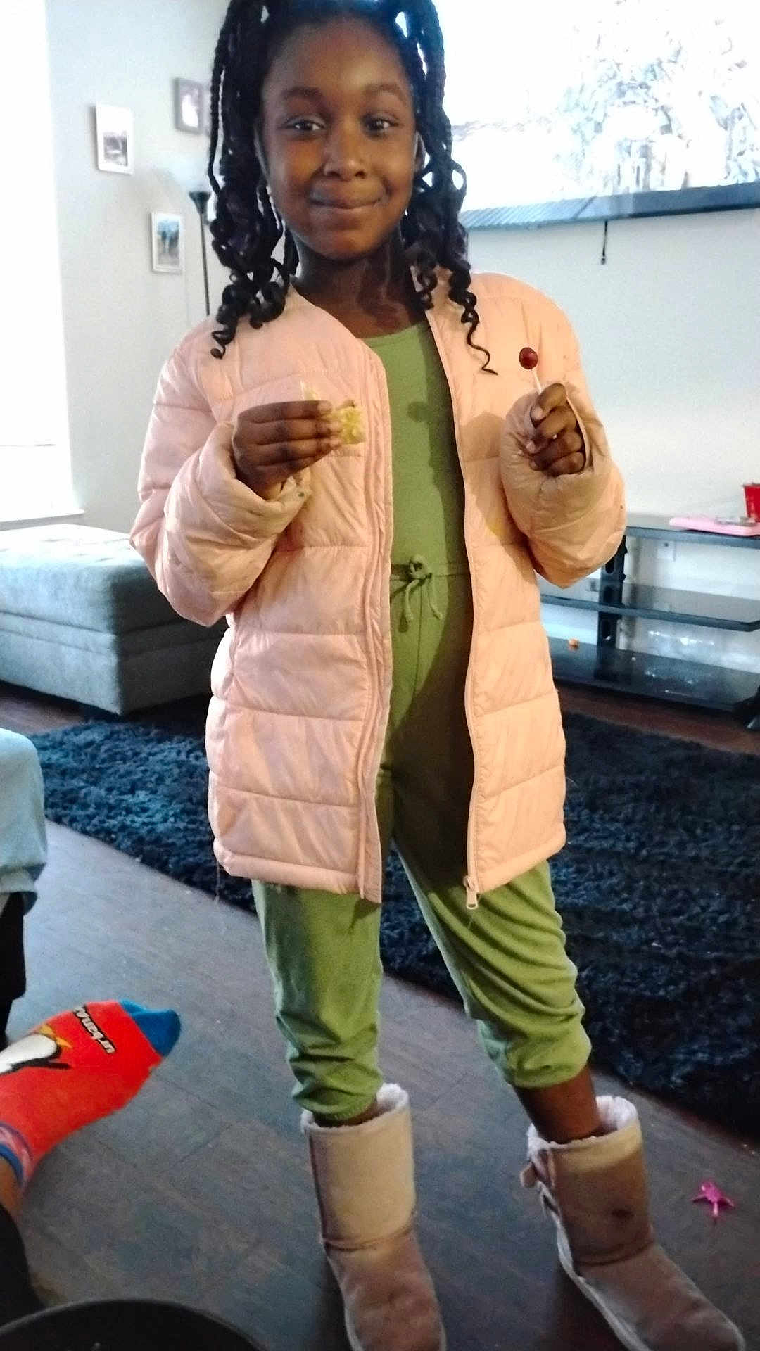 Unyque joined the competition — help win amazing prizes! child, girl, indoor, jacket, pink, green_clothing, boots, lollipop, snack, smiling, standing, hair, curly_hair, floor, rug, sofa, lamp, furniture, home, cozy