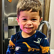 Grayson is registered to the contest to win money with this photo: appliance, child, clothing, dinosaur_shirt, face, hair, happy, home, indoor, kitchen, metal, person, portrait, refrigerator, seat, sitting, smiling, stainless_steel, toddler, young_child