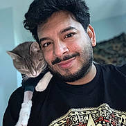 Mimikyu is registered to the contest to win money with this photo: affection, animal, beard, black_tshirt, cat, closeup, cozy, face, feline, friendly, happy, human, indoor, man, pattern, pet, portrait, shoulder, smile, young_adult