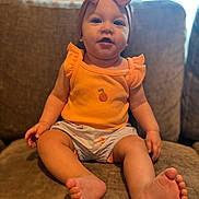 Everly joined the competition — help win amazing prizes! baby, child, infant, sitting, orange_top, headband, bow, couch, indoor, feet, toes, cute, portrait, happy, clothing, furniture, smile, person, young, relaxed