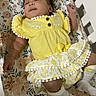 adorable, baby, baby_clothes, bed, child, comfort, crib, cute, floral_sheet, indoor, infant, peaceful, person, portrait, resting, sleeping, smiling, sock, yellow_dress, young_child