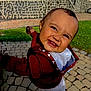 Lucas is registered to the contest to win money with this photo: toddler, child, smiling, hoodie, outdoor, grass, cobblestone, stone_wall, happy, face, person, daylight, cute, clothing, playful, young_child, casual, expression, teeth, hood