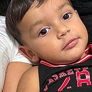 Anthony joined the competition — help win amazing prizes! child, toddler, face, eyes, lips, hair, skin, portrait, close_up, smile, ear, cheek, shirt, sportswear, red_trim, black_clothing, indoor, couch, arm, relaxed