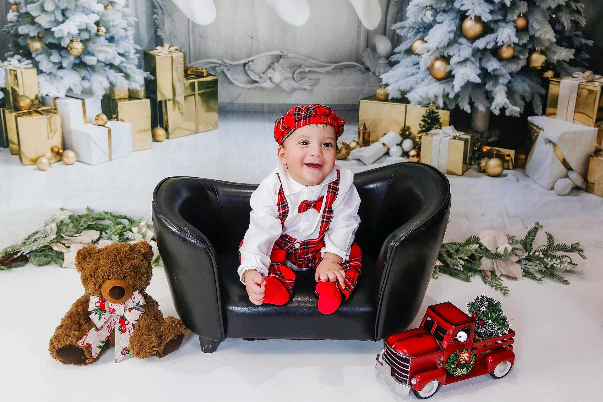 Thiago joined the competition — help win amazing prizes! baby, child, smiling, black_couch, red_plaid, hat, bowtie, teddy_bear, toy_truck, christmas_tree, christmas_decorations, wrapped_gifts, holiday, festive, indoor, portrait, happy, cute, seasonal, celebration