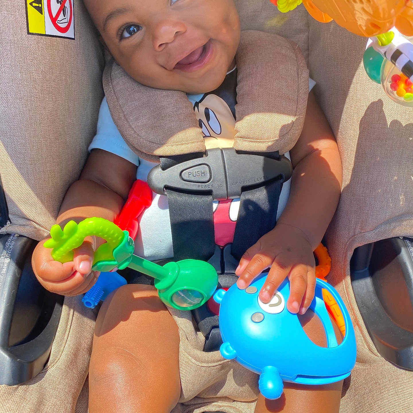 Deheir is registered to the contest to win money with this photo: baby, bright, car_seat, child, closeup, clothing, colorful, cute, daylight, hands, happy, indoors, infant, play, portrait, safety, seat, seatbelt, smiling, toy