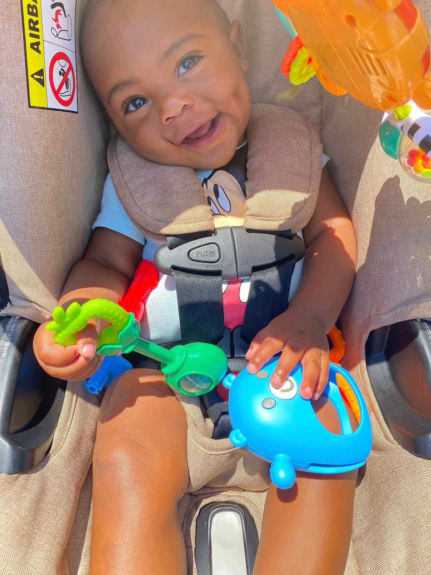 Deheir is registered to the contest to win money with this photo: baby, bright, car_seat, child, closeup, clothing, colorful, cute, daylight, hands, happy, indoors, infant, play, portrait, safety, seat, seatbelt, smiling, toy