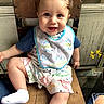 Cito is registered to the contest to win money with this photo: baby, child, smiling, sitting, chair, bib, clothing, dinosaur_print, sock, wood, window, flower, hair_curl, indoor, cute, happy, person, portrait, legs, casual