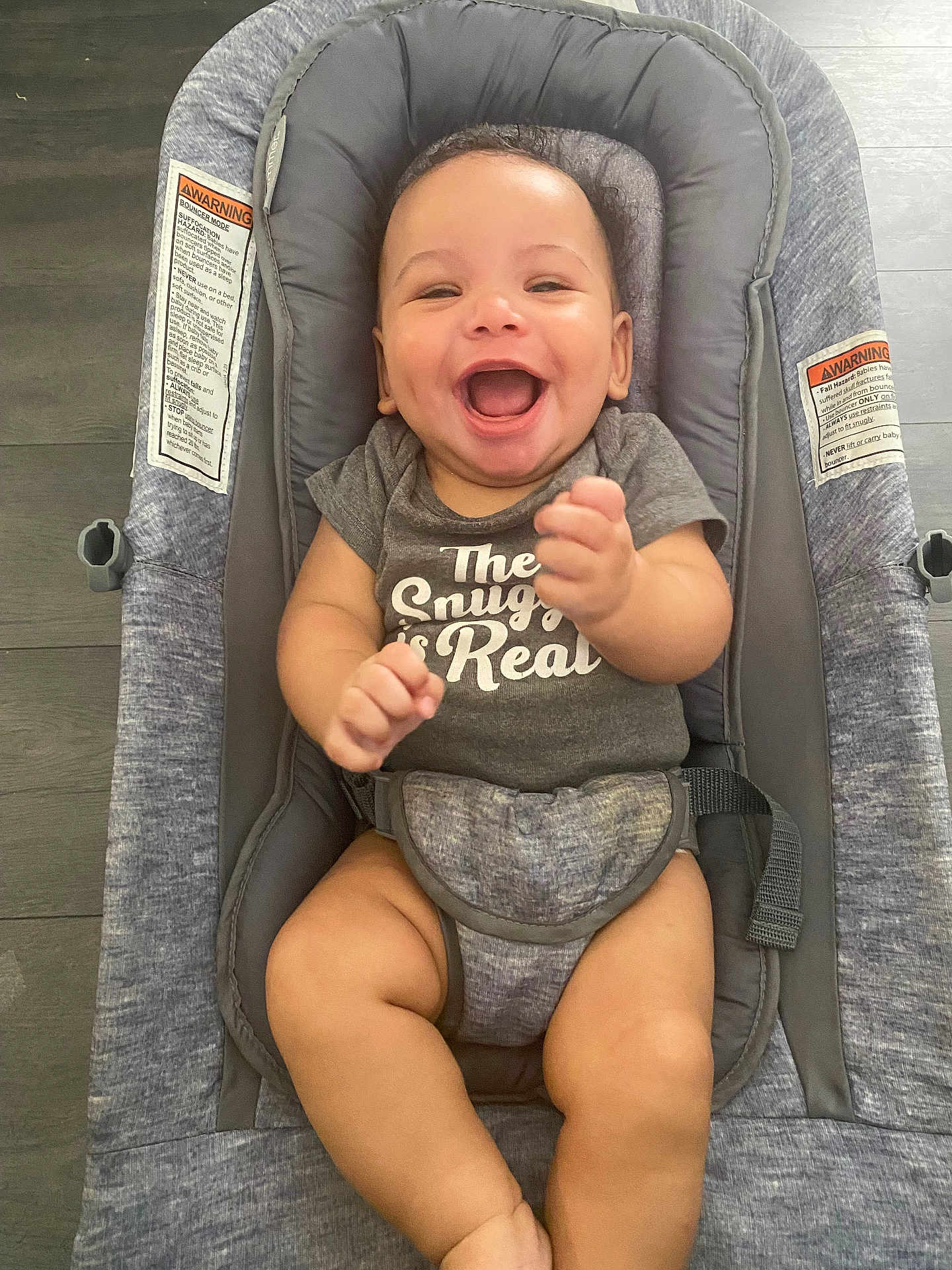 Brandon is registered to the contest to win money with this photo: baby, infant, smiling, laughing, onesie, baby_seat, cushion, gray, happy, child, indoors, floor, infant_clothing, cute, person, portrait, skin, seat_belt, baby_bouncer, sitting