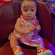 Clover is registered to the contest to win money with this photo: baby, child, sitting, dress, butterfly_pattern, sneakers, nike, orange, curly_hair, leather_chair, indoor, restaurant, bar, bottle, glass, person, cute, hands, expression, casual
