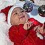 baby, child, christmas, holiday, santa_hat, red_clothing, ornaments, decoration, festive, blanket, cute, infant, portrait, celebration, smiling, hands, face, indoor, seasonal, happy