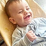 baby, smile, happy, infant, child, face, clothing, sweater, hand, fist, seat, cushion, indoor, cute, joy, young, person, portrait, skin, head