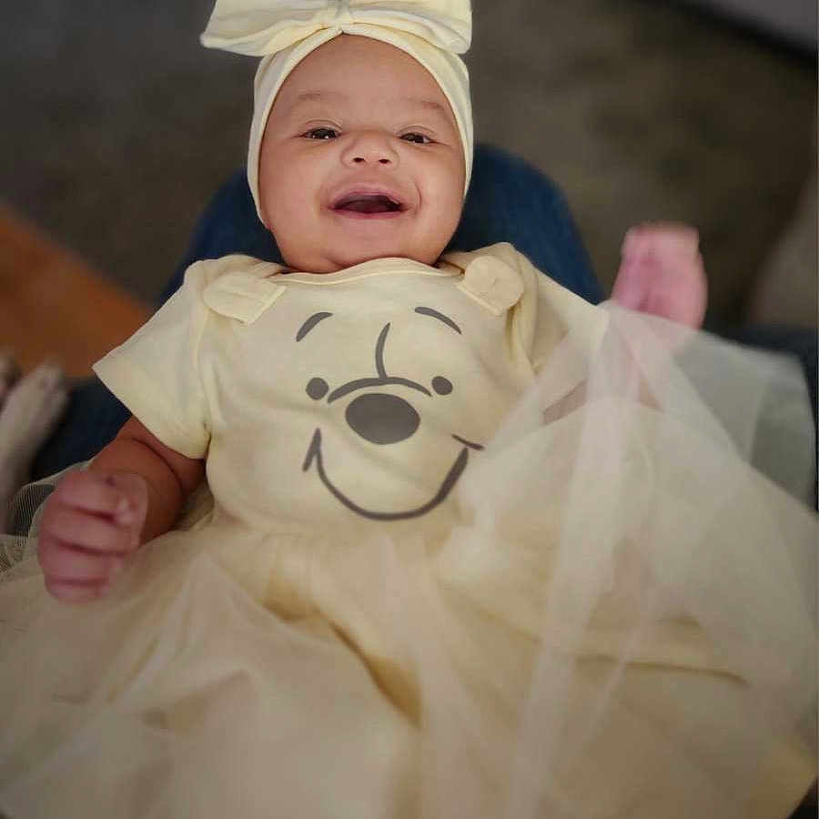 Normani is registered to the contest to win money with this photo: baby, babylaughing, bonnet, clothing, coat, costume, dress, face, fashion, formalwear, gown, happy, hat, head, newborn, pants, person, photography, portrait, smile