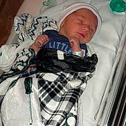 Marcus is registered to the contest to win money with this photo: newborn, baby, sleeping, blanket, hospital, bassinet, hat, pacifier, infant, child, hospital_tag, clothing, wrapped, peaceful, bed, resting, cute, indoors, person, medical