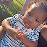 toddler, child, baby, curly_hair, striped_shirt, outdoor, grass, sunlight, hand, face, portrait, person, cute, sitting, clothing, daylight, expression, closeup, summer, casual