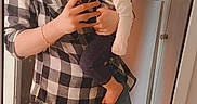 Lilith is registered to the contest to win money with this photo: woman, toddler, child, mirror, selfie, indoor, casual_clothing, plaid_shirt, jeans, barefoot, phone, smiling, holding_child, curly_hair, wooden_floor, door, home, portrait, happy, family