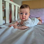 Eva participe au concours pour gagner de l'argent avec cette photo : baby, infant, bed, white_sheet, crib, blue_eyes, expression, curious, hand, face, person, indoor, pillow, sleepwear, toddler, nursery, skin, head, lying_down, soft_light