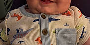 Ronin is registered to the contest to win money with this photo: baby, buttoned_shirt, cheeks, child, closeup, clothing, cozy, cute, dinosaur_pattern, eyes, face, happy, head, indoor, infant, onesie, person, portrait, sitting, smiling