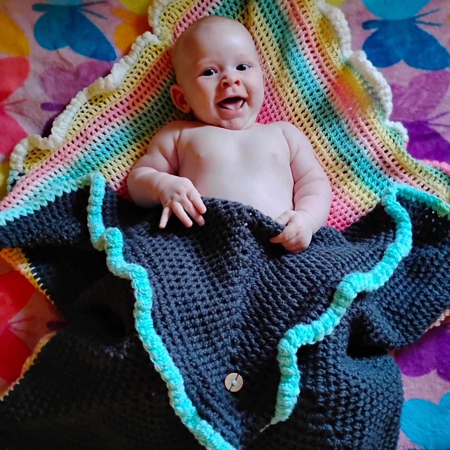 Willow joined the competition — help win amazing prizes! baby, blanket, butterfly_pattern, child, colorful, cozy, crocheted_blanket, cute, face, hand, happy, indoor, infant, lying_down, pattern, skin, smiling, textile, warm, young_child