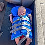 baby, life_jacket, pacifier, boat, barefoot, infant, sleeping, blue, safety, resting, seat, floor, strap, comfort, child, sunlight, closeup, relaxation, water_safety, outdoor