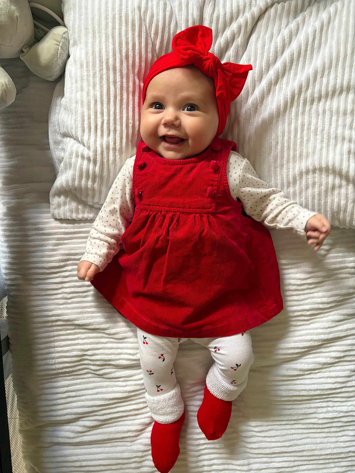 Arya a rejoint le concours — aidez-le/la à gagner de superbes lots ! baby, smiling, red_dress, headband, white_blanket, lying_down, happy, infant, cute, toddler, cozy, indoor, child, patterned_tights, red_socks, portrait, young_child, cheerful, face, clothing