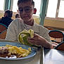 Soan a rejoint le concours — aidez-le/la à gagner de superbes lots ! banana, boy, cafeteria, casual, chair, child, food, fries, glasses, indoor, light, lunch, meal, person, plate, seated, smile, table, tray, window