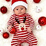 Lennie-Roy joined the competition — help win amazing prizes! baby, christmas, festive, santa_hat, red_and_white, striped_onesie, reindeer, ornaments, red_baubles, white_baubles, fluffy_background, holiday, cute, infant, lying_down, holding_object, celebration, seasonal, soft_texture, portrait