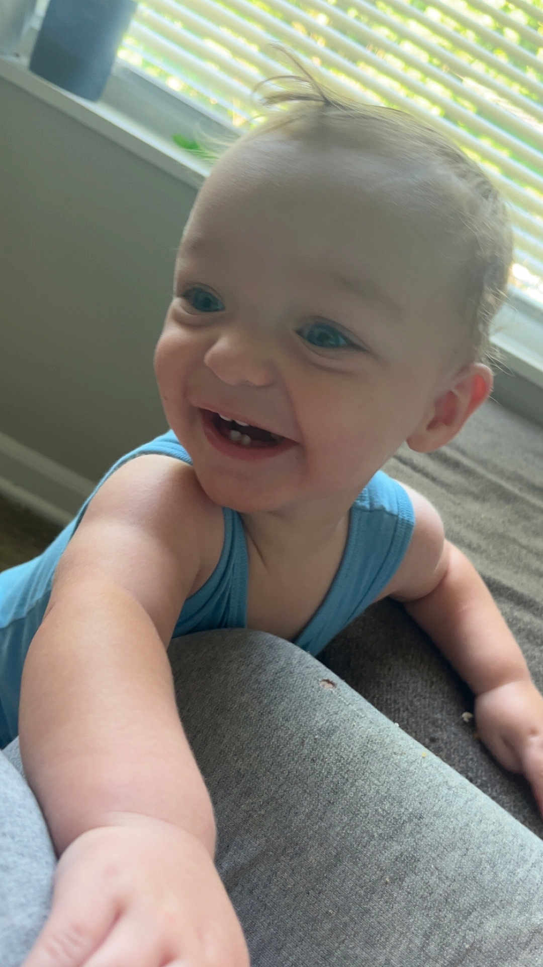Kohen joined the competition — help win amazing prizes! arm, baby, blinds, blue_tank_top, carpet, child, couch, expression, face, happy, home, indoor, light, person, reaching, skin, smiling, teeth, toddler, window