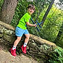 boy, casual_clothing, child, daylight, forest, green_shirt, happy, leaves, nature, outdoor, person, play, red_shoes, smile, stone_wall, summer, toy_airplane, trees, white_socks, young