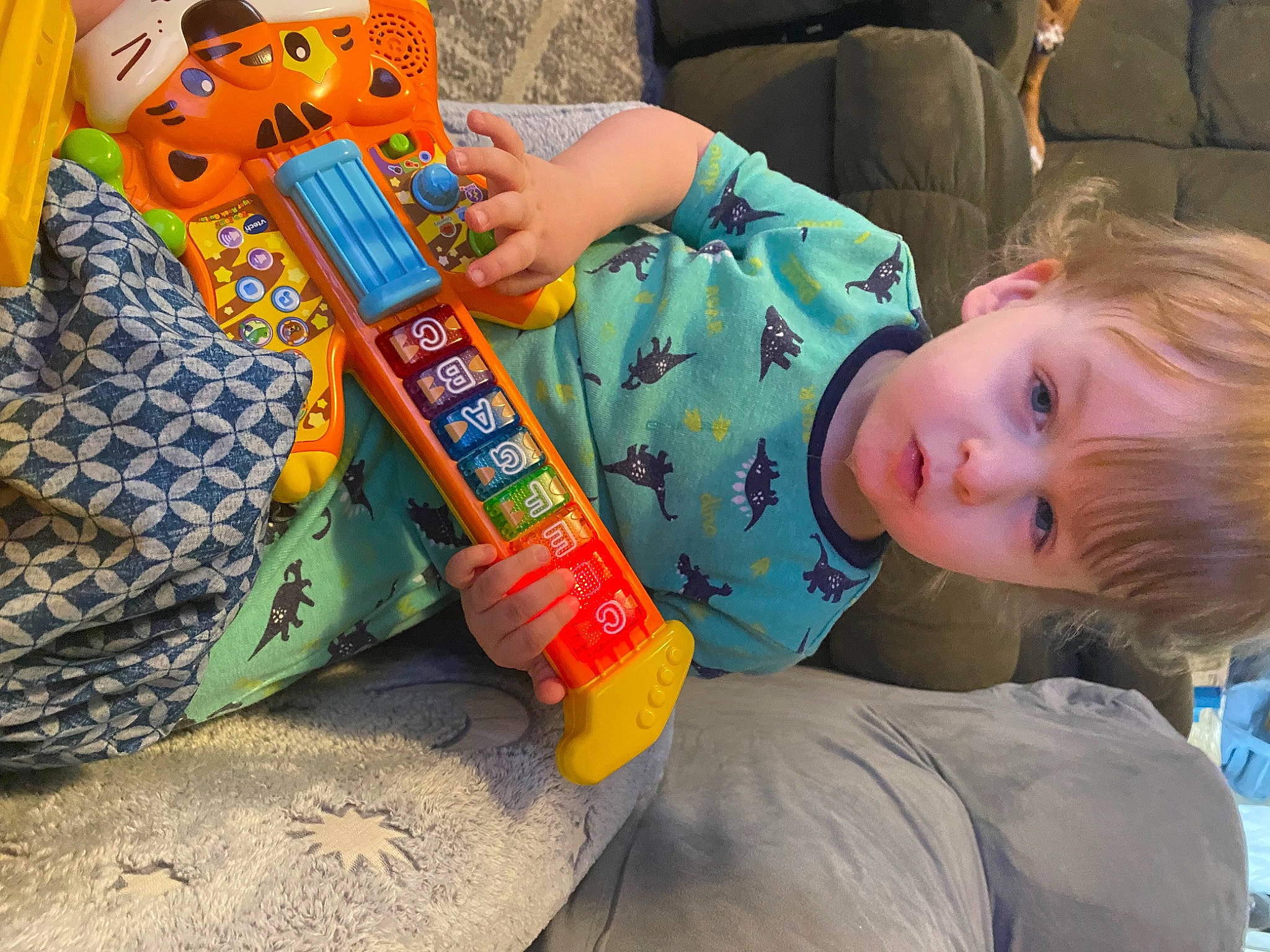 Caiden is registered to the contest to win money with this photo: baby, child, comfort, fun, lap, leisure, musical_instrument, person, plastic, plucked_string_instruments, recreation, room, sitting, string_instrument, toddler, toy