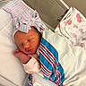 newborn, baby, sleeping, bow_hat, striped_hat, blanket, hospital, crib, swaddled, infant, child, cute, resting, peaceful, pink, white, blue, soft_lighting, face, hand
