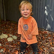 Albert is registered to the contest to win money with this photo: autumn_leaves, barefoot, blonde_hair, casual_clothing, child, cute, dirt, happy, nature, orange_tshirt, outdoor, person, playful, portrait, rustic_fence, sandals, smiling, standing, toddler, young_child