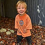 autumn_leaves, barefoot, blonde_hair, casual_clothing, child, cute, dirt, happy, nature, orange_tshirt, outdoor, person, playful, portrait, rustic_fence, sandals, smiling, standing, toddler, young_child