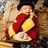 baby, sleeping, knitted_blanket, hat, wooden_bed, cushion, decor, books, flowers, cozy, indoors, peaceful, infant, wrapped, soft, floor, homedecor, child, cute, resting