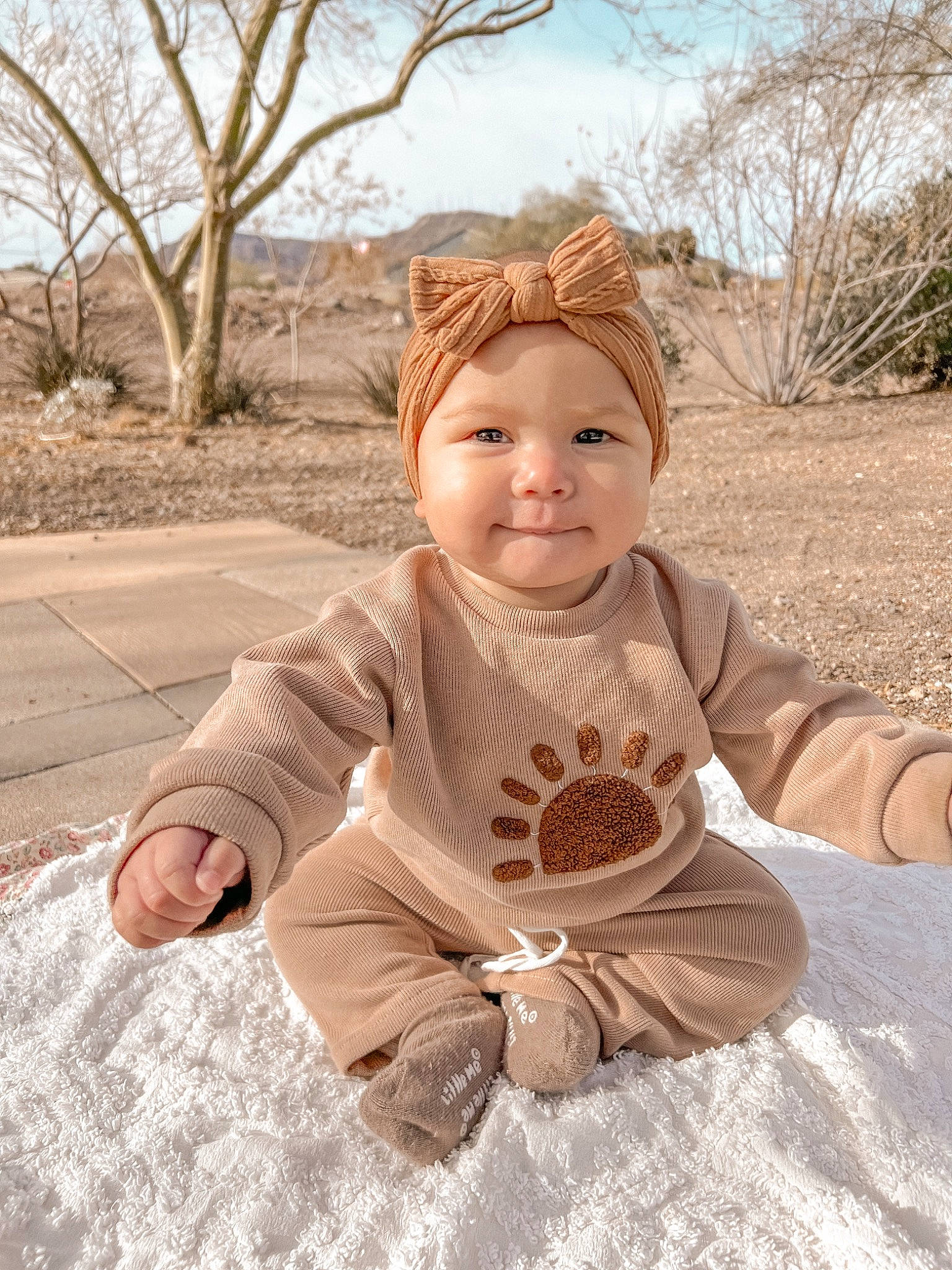 Ellie is registered to the contest to win money with this photo: baby, baby_toddler_clothing, child, face, fun, grass, happy, headwear, human_body, joy, leaf, pattern, people_in_nature, person, plant, sitting, sky, sleeve, smile, toddler