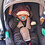 baby, car_seat, pacifier, winter_clothing, hat, snowsuit, infant, child, seatbelt, black_clothing, fuzzy_hat, indoor, cute, small_child, warm_clothes, sitting, baby_accessory, child_safety, cozy, adorable