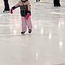 child, ice_skating, helmet, pink_gloves, winter_clothing, indoor_rink, ice, people, skates, sport, activity, cold_weather, jacket, pants, helmet_strap, skating, recreation, balance, fun, leisure
