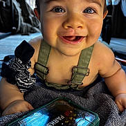 Rafaël participe au concours pour gagner de l'argent avec cette photo : baby, infant, smiling, face, child, overalls, towel, toy, toolbox, indoor, closeup, happy, person, clothing, hand, eyes, skin, expression, black_and_white, fabric