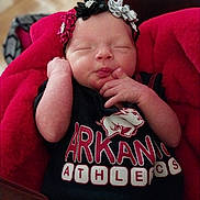 Catalaya is registered to the contest to win money with this photo: baby, newborn, infant, sleeping, headband, flower_headband, blanket, red_blanket, closed_eyes, hand, fingers, portrait, face, cheeks, tshirt, logo, indoors, cozy, adorable, soft_texture