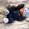 newborn, baby, sleeping, infant, portrait, bassinet, blanket, cushion, hat, knit_cap, navy_clothing, white_socks, gold_chain, nursery, bedding, soft_lighting, indoors, peaceful, resting, closeup